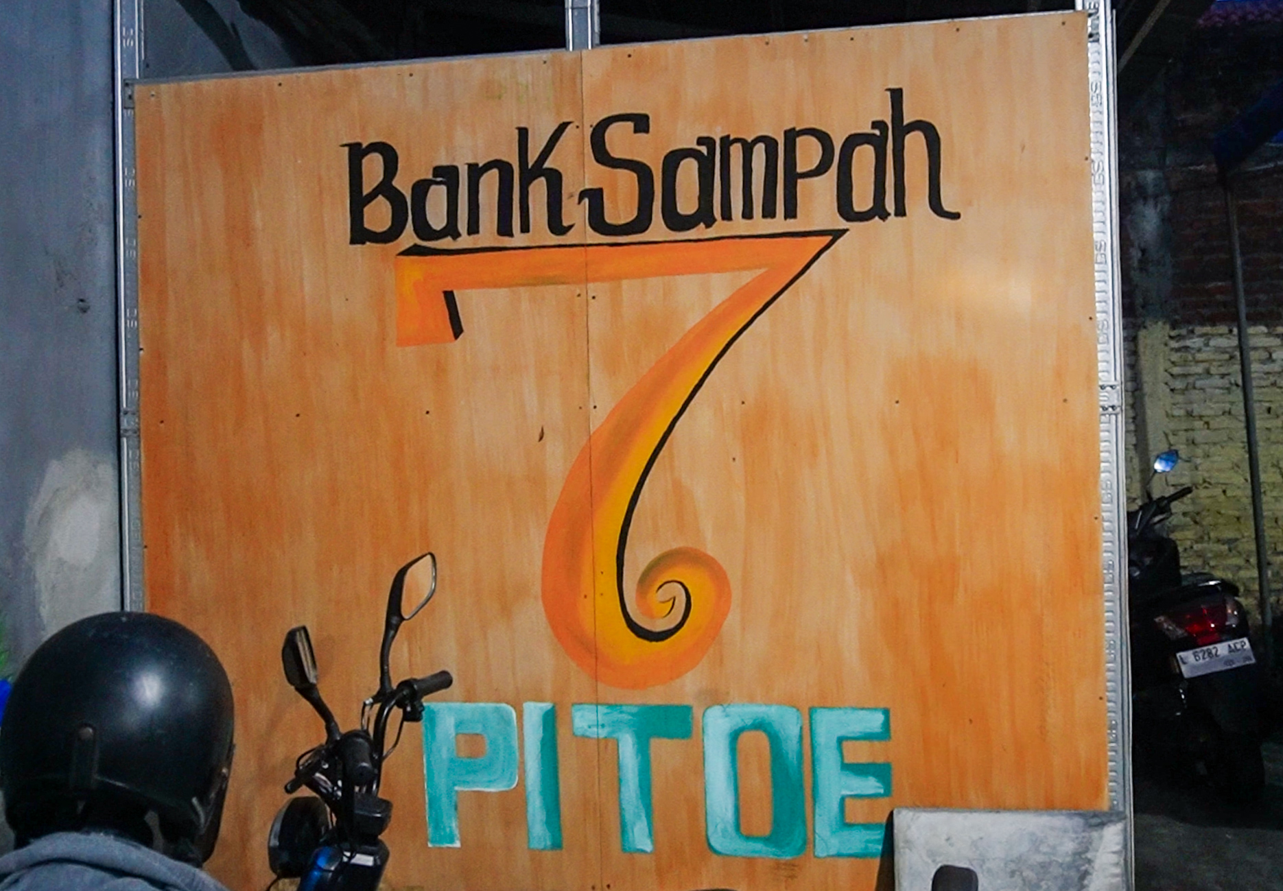 Wooden sign with Bank Sampah text and number 6