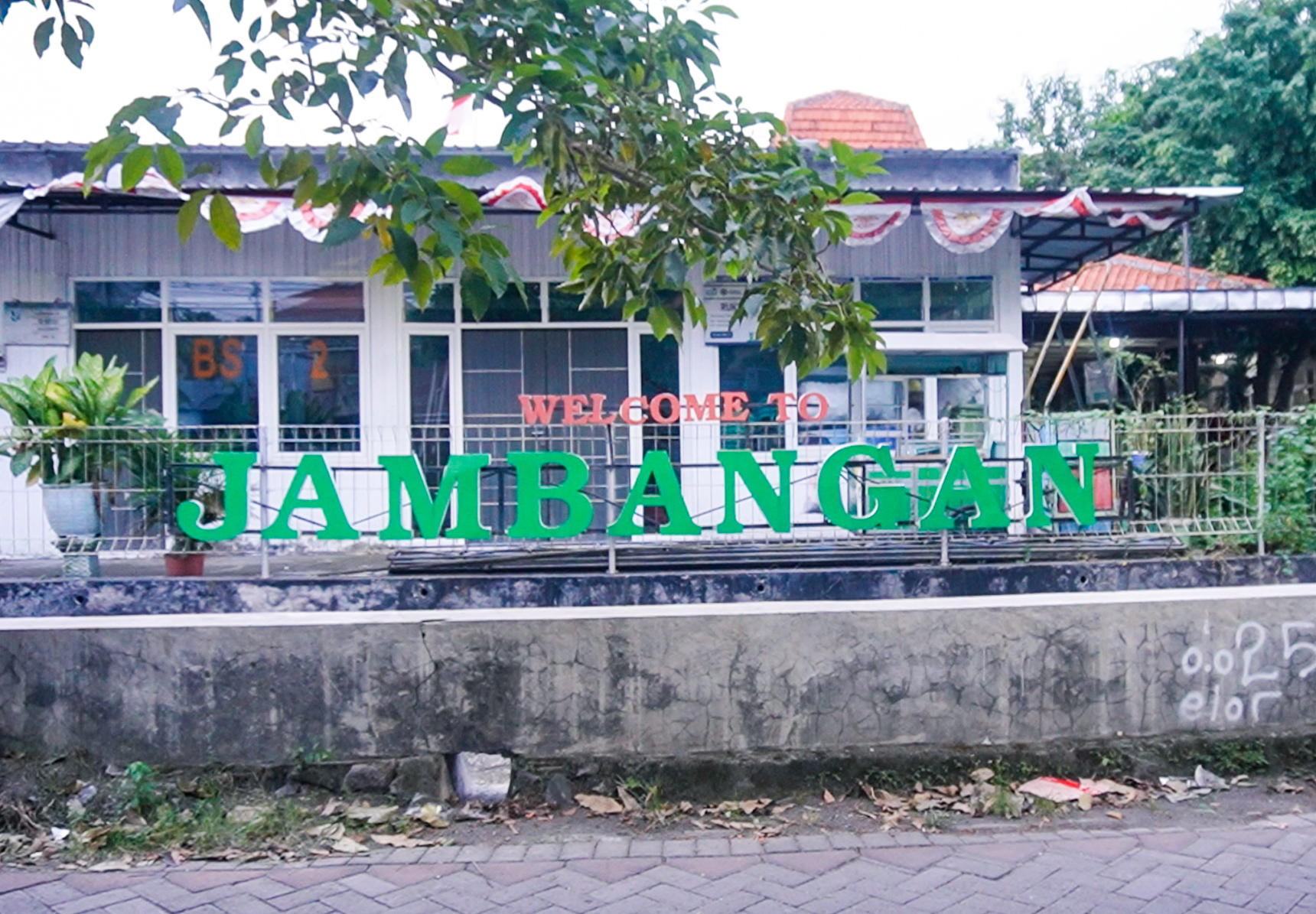 Wall with graffiti Welcome to Jambangan in green letters and plants