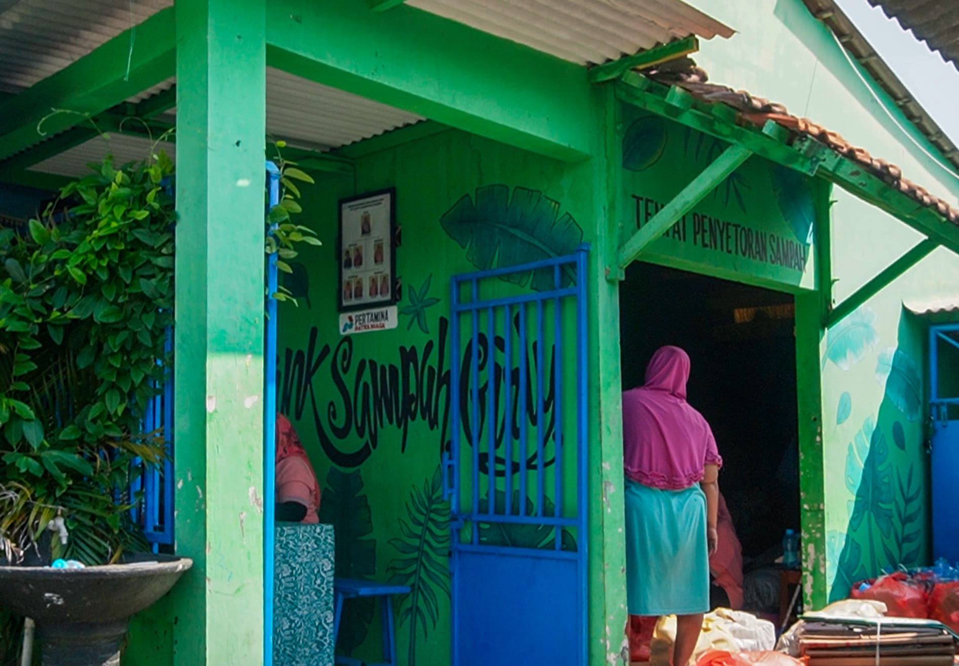 Green building with mural and person walking inside